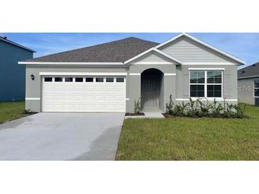 Charming single-story home featuring a two-car garage, neutral color palette, and manicured lawn at 4212 Evernia Rd, Tavares, FL 32778