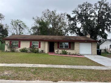 Charming single-story home features a brick facade, red shutters, attached garage, and a well-manicured front yard at 4571 La Vista Rd, Orlando, FL 32808