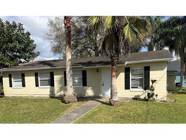 Charming single-story home with well-maintained lawn, complemented by palm trees and black shutters at 935 Florence Ave, Orlando, FL 32811