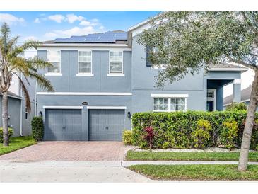Two-story home featuring a two-car garage, solar panels, well-maintained landscaping, and a charming blue facade at 15373 Murcott Harvest Loop, Winter Garden, FL 34787