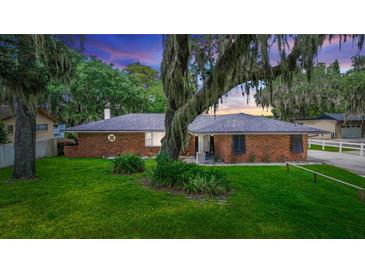 Charming brick home with a well-manicured lawn and mature trees creating a serene setting at 5584 N Dean Rd, Orlando, FL 32817