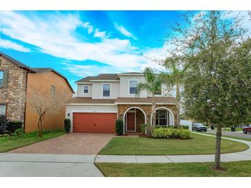 Charming two-story home featuring stone accents, a brick driveway, and a well-manicured lawn at 1077 Fountain Coin Loop, Orlando, FL 32828