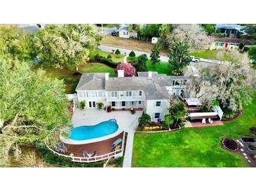 Expansive property featuring a pool with a deck, lush greenery, and a charming, light-colored two-story home at 1400 Tedford St, Eustis, FL 32726