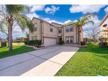 Charming two-story home with a well-manicured front lawn, mature trees, and a driveway leading to a two-car garage at 2260 The Oaks Blvd, Kissimmee, FL 34746