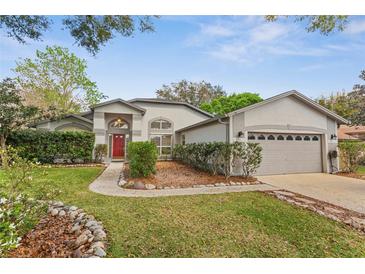 Charming single-story home featuring a well-manicured lawn, stone accents, and a red front door at 2856 Broward Ct, Oviedo, FL 32765