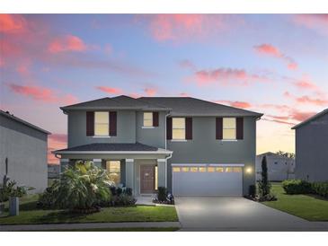 Two-story home featuring a two-car garage, covered porch, and landscaped front yard at sunset at 5226 Mahogany Dr, Mount Dora, FL 32757