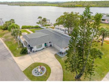 Waterfront home featuring well-manicured lawn, long driveway, mature trees, and vibrant blue front door at 716 Palm Circle Dr, Port Orange, FL 32127