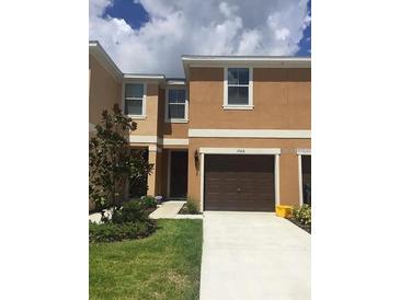 Two-story townhome with an attached single car garage and a well-manicured front lawn and landscaping at 1560 Chelsea Dr, Davenport, FL 33897