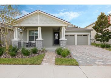 Charming single-Gathering home featuring a covered front porch, brick driveway, and a two-car garage at 16410 Taliesin St, Winter Garden, FL 34787