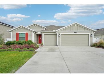 Charming single-story home featuring a well-manicured lawn, red door, red shutters, and a two-car garage at 5269 Red Coral Cir, Mount Dora, FL 32757
