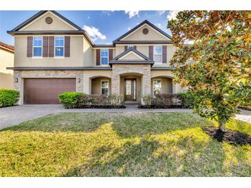 Charming home featuring a stone accented entryway, attached garage, and well-maintained landscaping at 10024 John Adams Way, Orlando, FL 32817