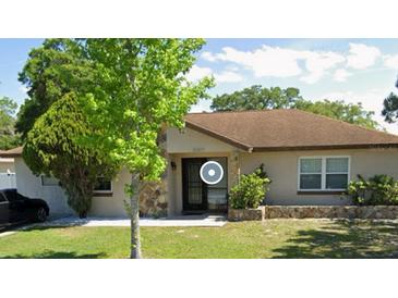 Charming single-story home featuring stone accents, a well-manicured lawn, and mature trees at 12927 Montana Woods Ln, Orlando, FL 32824