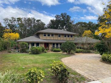 Charming two-story home with a well-manicured lawn, mature trees, and a circular brick driveway at 1606 The Oaks Dr, Maitland, FL 32751