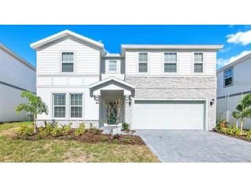 Charming two-story home with stone accents, paved driveway, manicured landscaping, and attached two car garage at 2004 Summer Dr, Davenport, FL 33897