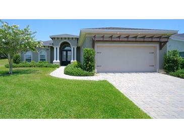 Charming single-story home with a manicured lawn, a pergola over the garage, and a double door entrance at 202 Stargrass Dr, Auburndale, FL 33823