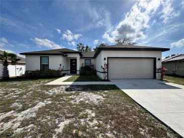 A white one story home with a two car garage, lawn, and walkway leading to the front door at 345 Gardenia Ct, Kissimmee, FL 34759