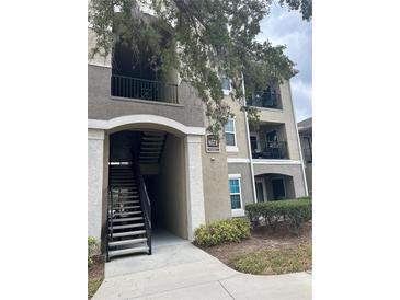 Multi-story condo building featuring private balconies, stairs to upper floors, and manicured landscaping at 6572 Swissco Dr # 22, Orlando, FL 32822