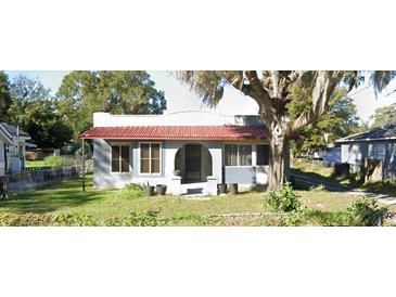 Charming single-story home with a vibrant red roof and a well-maintained front yard with mature landscaping at 963 26Th Nw St, Winter Haven, FL 33881