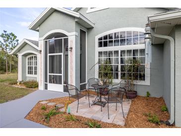 Charming home exterior with large windows, screened entrance and outside seating at 1045 S State Road 415, New Smyrna Beach, FL 32168