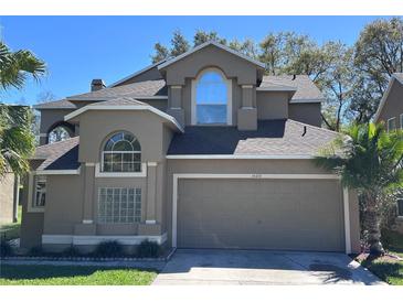 Charming home featuring a two-car garage, arched windows, and well-maintained landscaping at 14218 Squirrel Run, Orlando, FL 32828