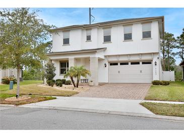 Two-story home featuring a manicured lawn, brick driveway, and attached two-car garage at 14384 Alafaya Oak Bnd, Orlando, FL 32828