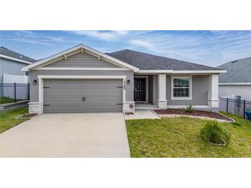 Charming single-story home featuring a two-car garage, manicured lawn, and inviting front entry at 1760 Astrid Rd, Davenport, FL 33837