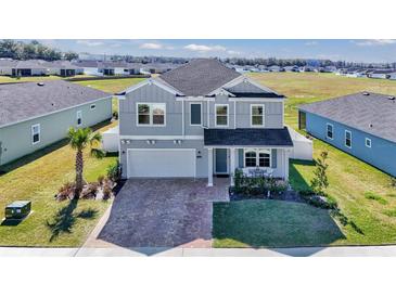 Charming two-story home with gray siding, manicured lawn, and brick paved driveway at 1795 Nw 44Th Ct Rd, Ocala, FL 34482