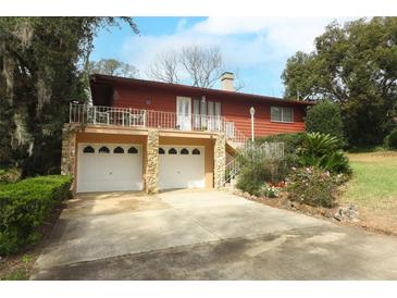 Charming raised home featuring a two-car garage and a welcoming front porch with white railings and a concrete driveway at 400 Ruth St, Longwood, FL 32779