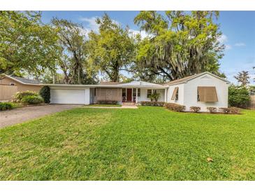 Charming single-story home with a lush green lawn and a brick-paved driveway at 5569 Jessamine Ln, Orlando, FL 32839
