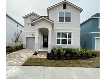 Charming two-story home features a well-manicured front yard with a stone-paved driveway at 8914 Caroline Bay Ct, Kissimmee, FL 34747