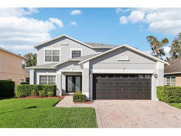 Charming two-story home with a well-manicured lawn, brick walkway, and a two-car garage at 128 Calabria Springs Cv, Sanford, FL 32771