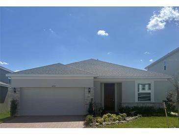 Charming single-story home with stone accents, a well-manicured lawn, and a two-car garage at 14709 Erice Ave, Clermont, FL 34714