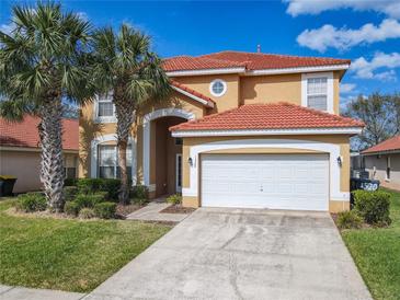 Charming two-story home with a red tile roof, well-manicured lawn, and lush landscaping including palm trees at 1520 Solana Cir, Davenport, FL 33897