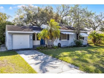 Charming single-story home with a well-manicured lawn, mature landscaping, and a classic blue door at 303 S Forest Ave, Orlando, FL 32803