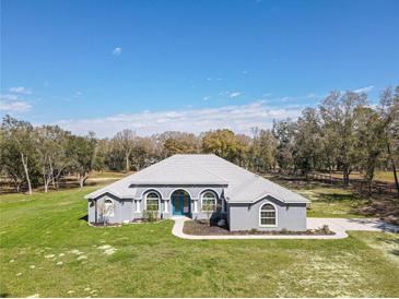 Charming home featuring a blue door, arched windows, and lush green lawn at 10688 Sw 129Th Terrace Rd, Dunnellon, FL 34432