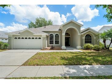 Charming single-story home featuring an arched entryway, well-manicured lawn, and a two-car garage at 16224 Magnolia Hill St, Clermont, FL 34714