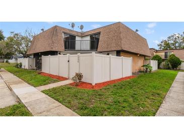 Charming townhouse featuring a white fence, well-manicured lawn, and a second-story balcony at 4036 Shannon Brown Dr, Orlando, FL 32808