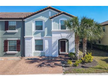 Charming two-story townhome featuring a light blue facade, red tile roof, and well-maintained landscaping at 4594 Terrasonesta Dr, Davenport, FL 33837