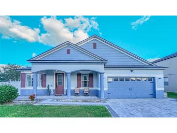 Charming single-story home featuring a covered porch, attached two-car garage, and well-manicured lawn at 523 Cascading Creek Ln, Winter Garden, FL 34787