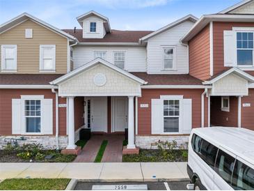 Charming townhouse exterior featuring red and tan siding, white trim, and well-maintained landscaping at 7558 Sunflower Cir, Kissimmee, FL 34747