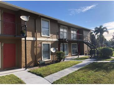 The apartment building features a brown exterior, red doors, and a staircase leading to the upper level units at 1909 Caralee Blvd # 4, Orlando, FL 32822