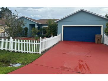 Charming single-story home with blue exterior, red driveway, blue garage door and white picket fence at 214 Great Yarmouth Ct, Kissimmee, FL 34758