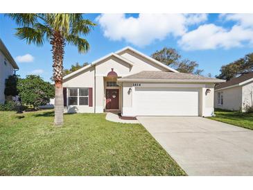 Charming single-story home featuring a well-manicured lawn, two-car garage, and inviting entryway with decorative touches at 2614 Brookshire Ct, Kissimmee, FL 34746