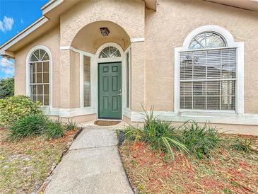 Exterior view of a home featuring a striking green front door, arched windows and well-maintained landscaping at 310 Sunvista Ct, Sanford, FL 32773