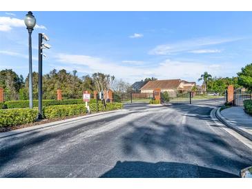 Gated community entrance with brick columns, black wrought iron gates, and mature landscaping at 3664 Sickle St, Orlando, FL 32812