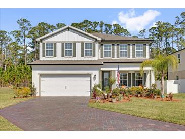 Charming two-story home with a brick driveway, a two car garage, green shutters and lush landscaping at 3916 Clipstone Pl, Sanford, FL 32773