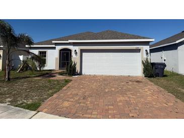 Charming single-story home with a brick driveway and a two-car garage at 622 Samuel Pl, Davenport, FL 33837