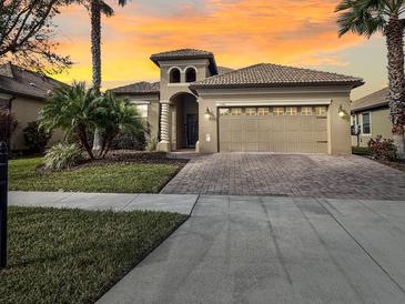 Stunning home featuring a paver driveway, two-car garage, and well-maintained landscaping with palm trees at 1304 Sea Pines Way, Davenport, FL 33896