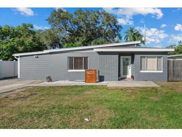 Charming gray home featuring a unique roof line, gray brick accents, and manicured landscaping at 1627 Triangle Ave, Orlando, FL 32806