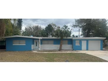 Charming single-story home with blue siding, white brick, a palm tree, and an attached one-car garage at 1907 Rockwell Rd, Orlando, FL 32808